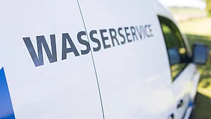 Nahaufnahme eines Servicefahrzeugs mit der Aufschrift „Wasserservice“ auf der Fahrzeugseite.
