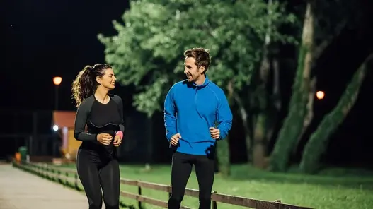 Zwei Jogger auf einem gut beleuchteten Weg.