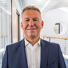 Portraitbild von Jürgen Noch im Anzug im Büro stehend