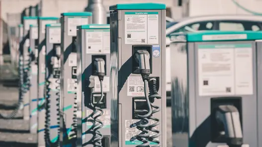 Eine Reihe von Ladesäulen mit Kabeln und Infotafeln bietet Ladeinfrastruktur für mehrere Elektrofahrzeuge gleichzeitig.