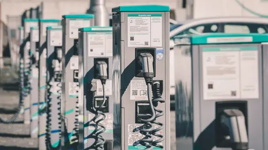 Eine Reihe von Ladesäulen mit Kabeln und Infotafeln bietet Ladeinfrastruktur für mehrere Elektrofahrzeuge gleichzeitig.