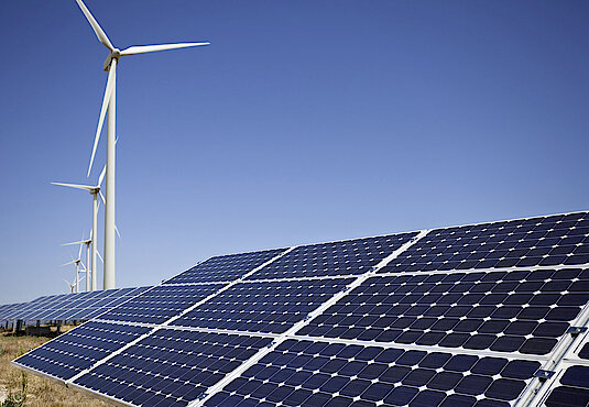 Solar-Panel mit Windrädern im Hintergrund