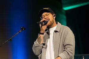 Musikalischer Beitrag von Batomae Der Sänger Batomae singt mit Mikrofon auf der Bühne, während des Rahmenprogramms der Preisverleihung.