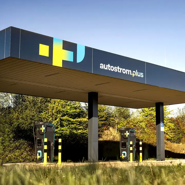 Zwei überdachte Ladestationen von autostrom.plus mit jeweils zwei Ladepunkten stehen an einem grünen Rastplatz an der Autobahn