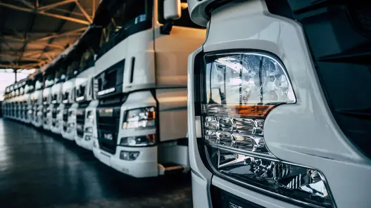 Reihe moderner LKW steht in einer Fahrzeughalle, fokussiert auf die Fahrzeugfront.
