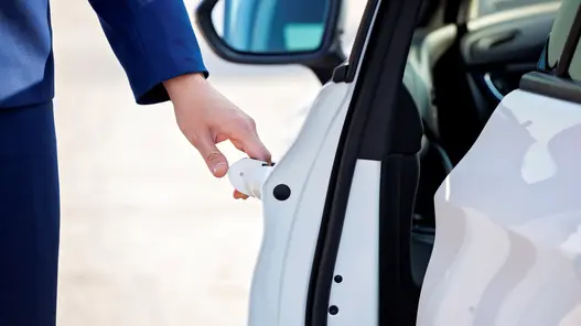 Eine Person öffnet die Tür eines weißen Elektroautos – bereit für die nächste Fahrt mit Schnellladung.