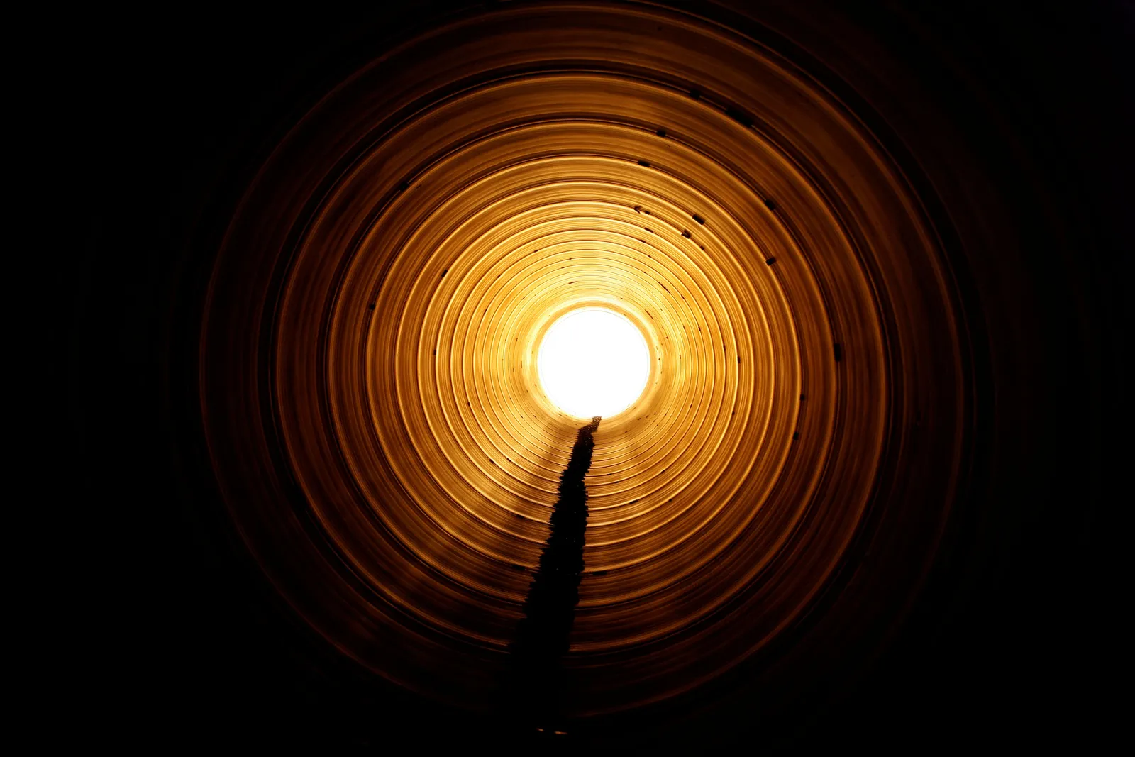 Eine Pipeline wurde von innen fotografiert und durch die Öffnung strahlt die Sonne herein.