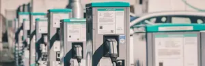 Eine Reihe von Ladesäulen mit Kabeln und Infotafeln bietet Ladeinfrastruktur für mehrere Elektrofahrzeuge gleichzeitig.