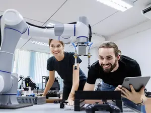 Zwei Mitarbeitende arbeiten an einem Roboter.