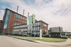 Firmengebäude im Hintergrund mit Fahnen und Mast im Vordergrund 