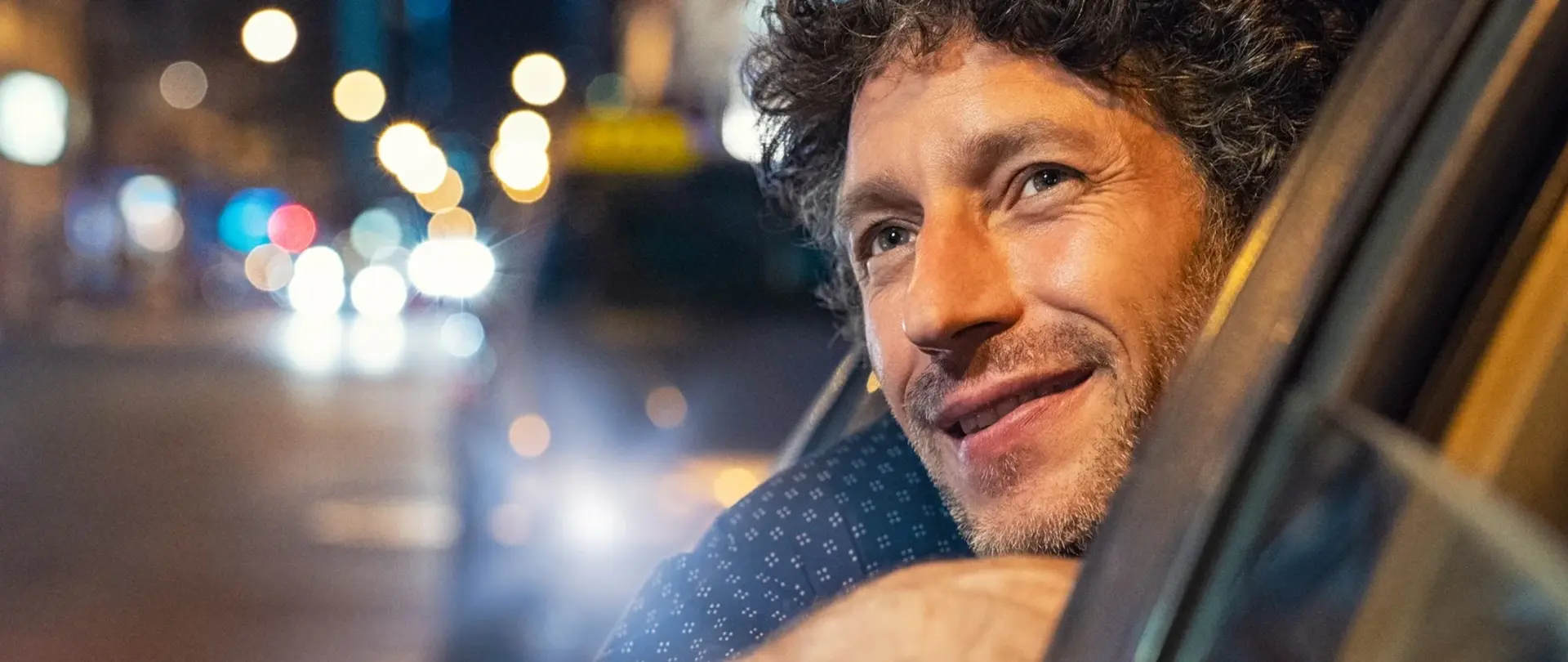 Mann schaut aus einem Auto der Straßenbeleuchtung entgegen