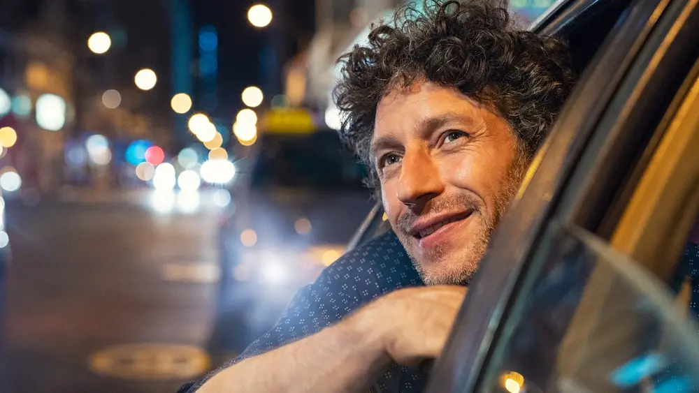 Mann schaut aus einem Auto der Straßenbeleuchtung entgegen