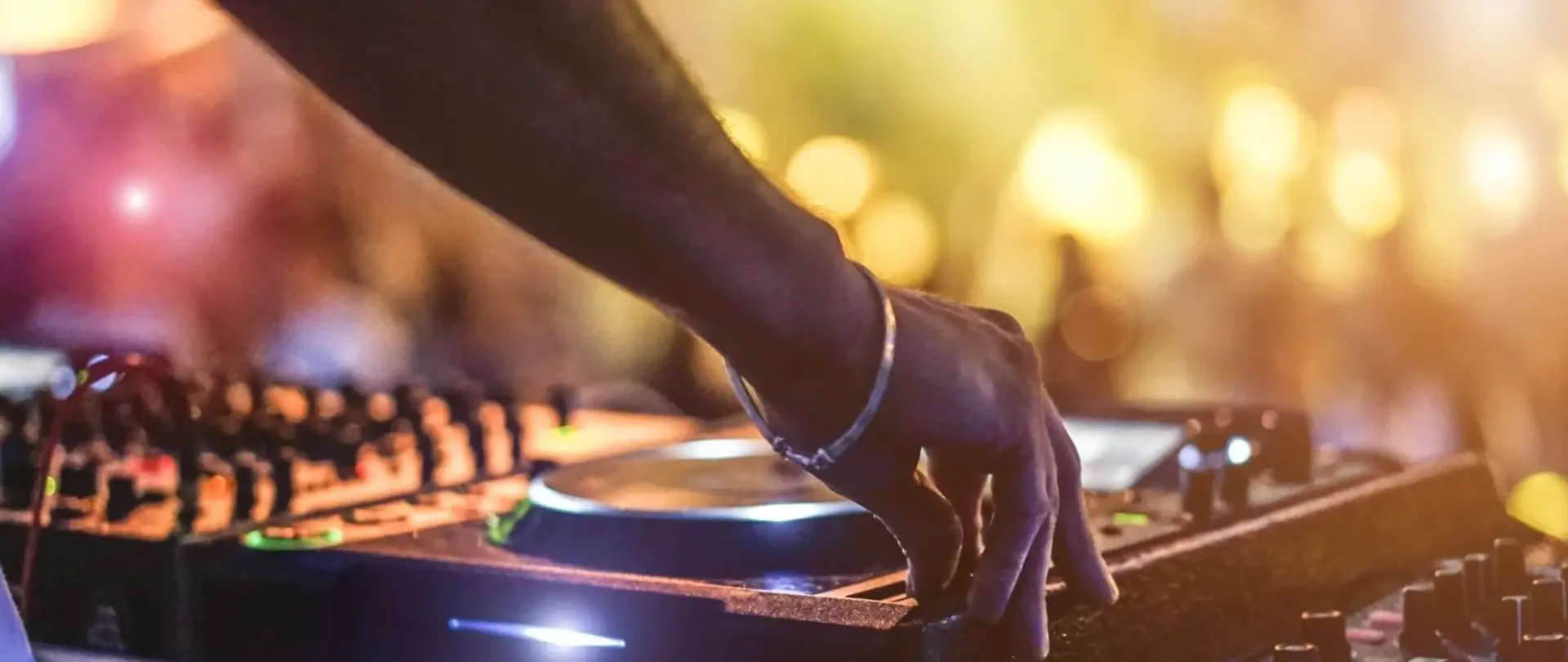 Westfalen Weser Kulturpreis Header. Ein DJ steht am Mischpult und betätigt diesen. Im Hintergrund sieht man ein großes Publikum - unscharf und in warmen Licht getaucht.