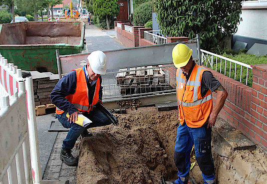 Monteure verlegen Bodenleitungen in einer Baustelle