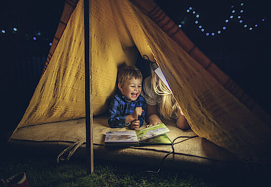 Kind mit Buch in einem Zelt