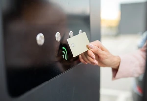 Eine Person hält eine Karte vor ein kontaktloses Zahlungsterminal mit grünem Signal-Icon.